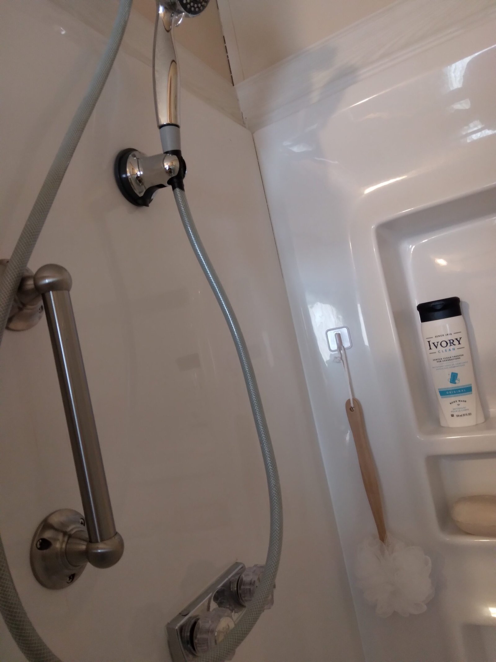 Stainless steel grab bars installed on two walls of a shower