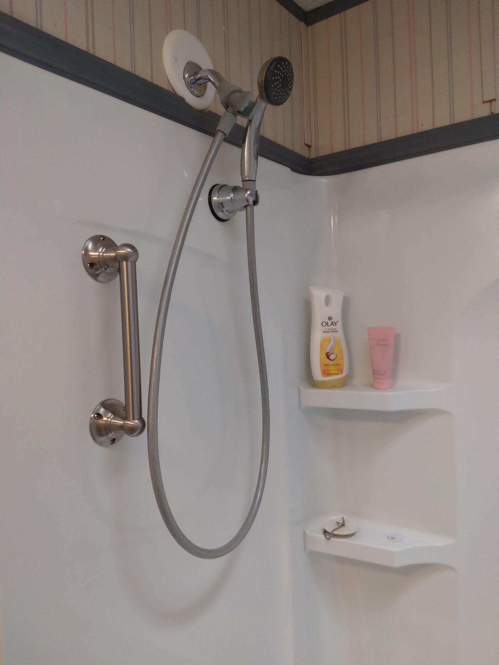 Vertical and angled stainless steel grab bars installed in a shower