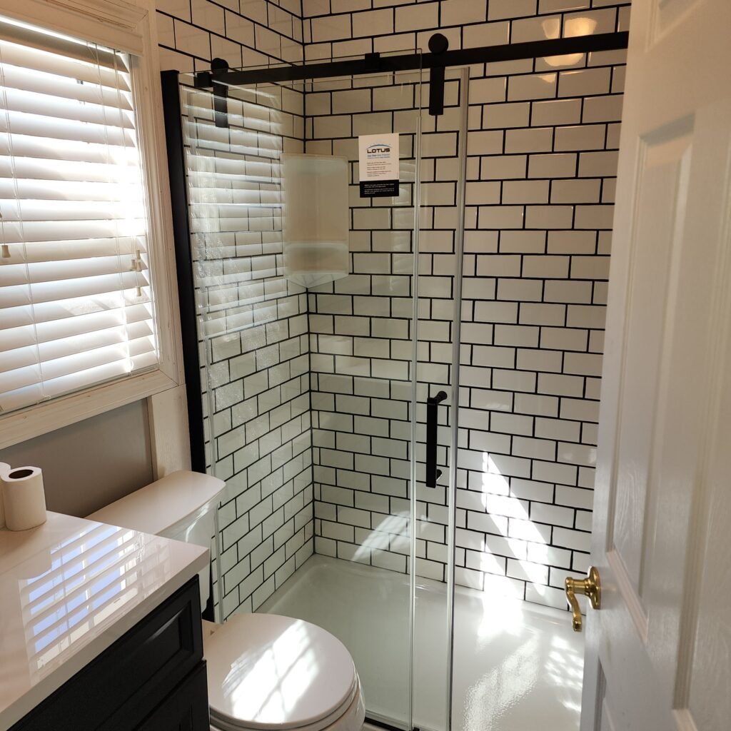 Black framed sliding glass shower enclosure in a tiled bathroom