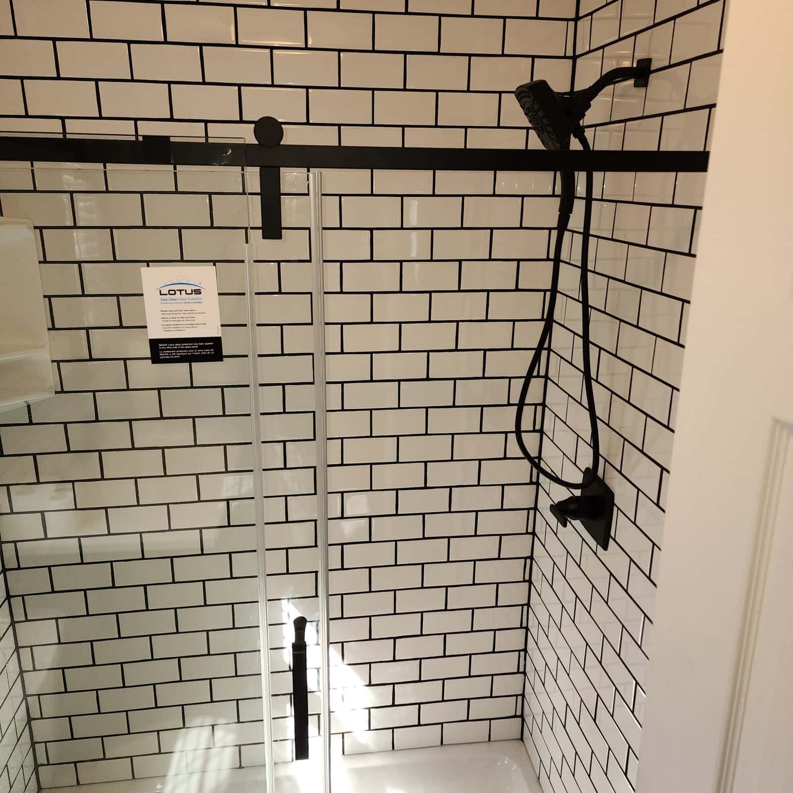 White subway tile shower wall with black fixtures and a recessed niche