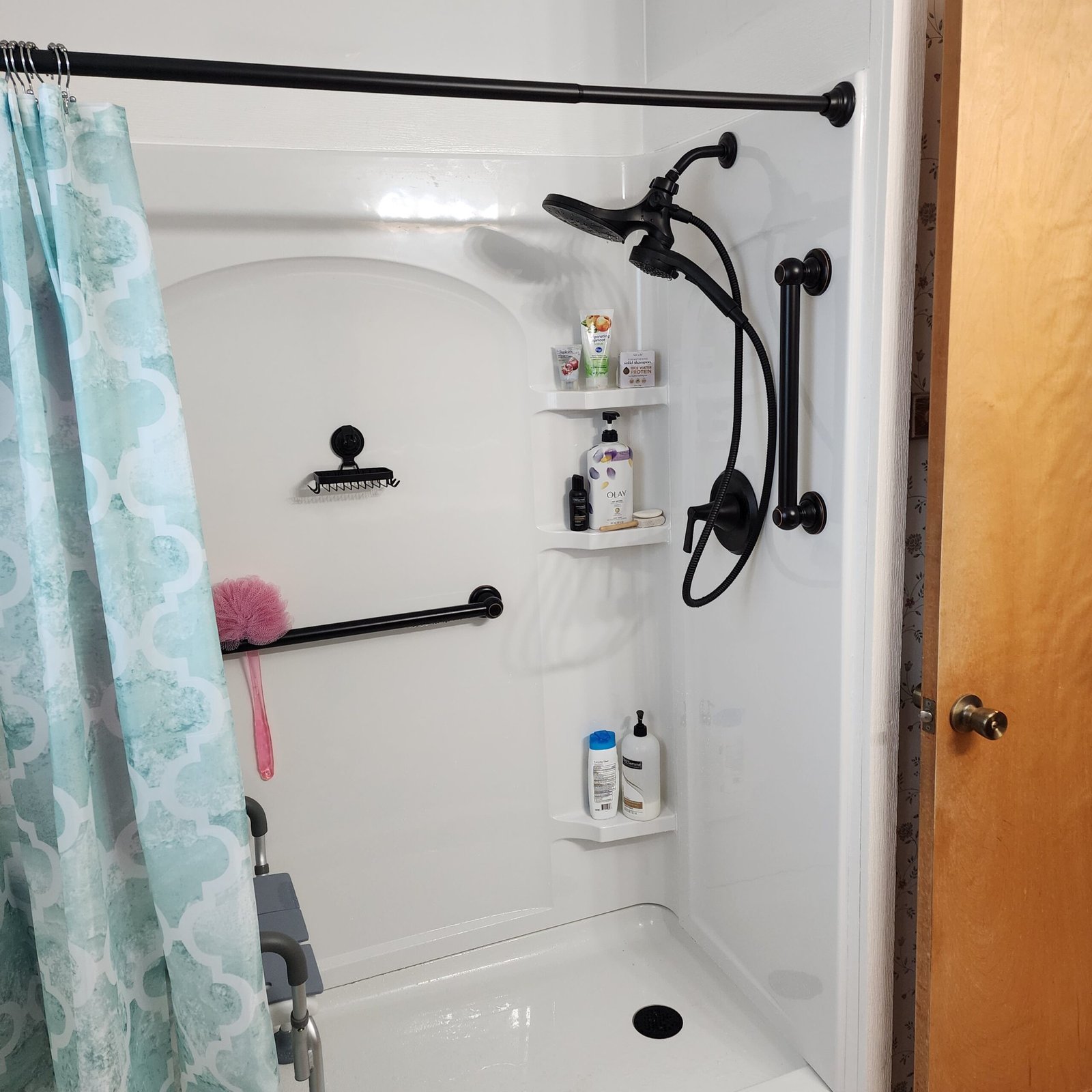 Black grab bars installed inside a white bathtub and shower surround