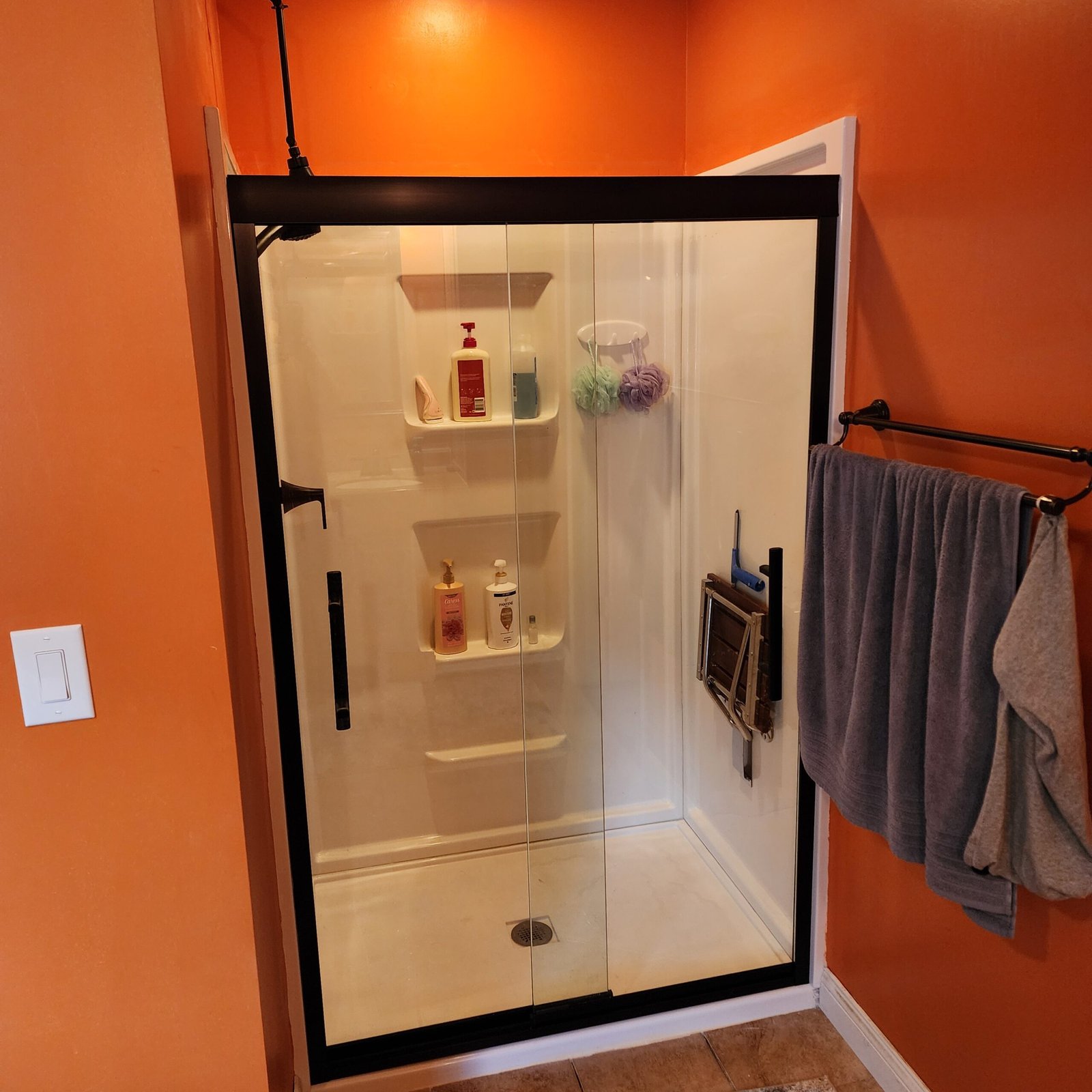 Black framed sliding glass shower door installed on a white shower