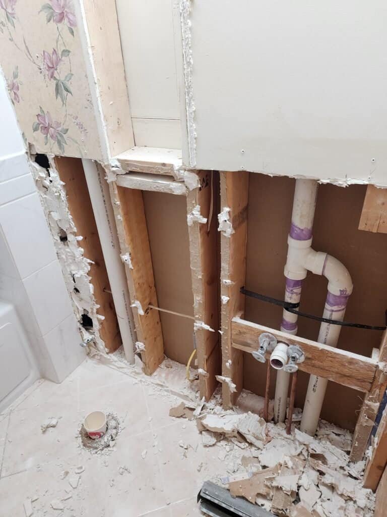 Bathroom wall opened during remodeling with plumbing and wall framing visible