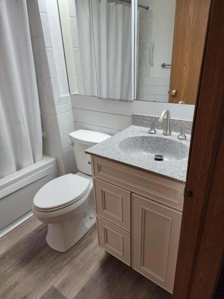 Finished bathroom with light-colored vanity, toilet, gray floor, mirror, and bathtub