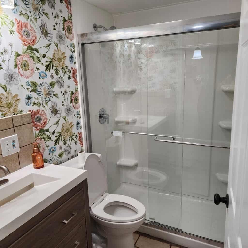 Finished bathroom with vanity, mirror, toilet, and glass shower enclosure