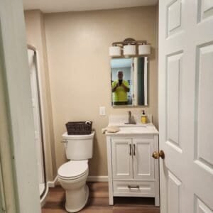 Finished bathroom remodeling view with a worker reflected in the mirror